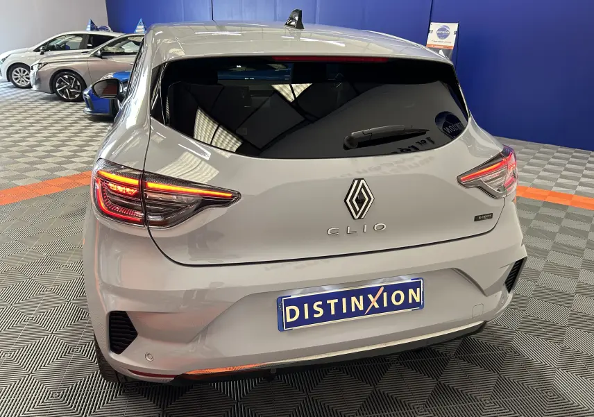 Vue arrière d'une Renault Clio V gris Rafale métal avec feux allumés dans un showroom.