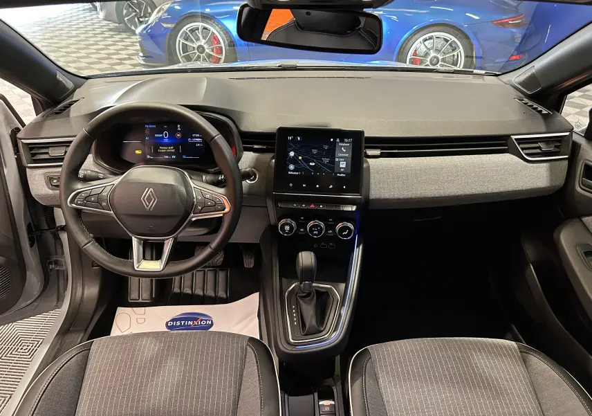 Intérieur de la Renault Clio V hybride 2025, vue frontale du tableau de bord avec écran tactile et volant multifonction.