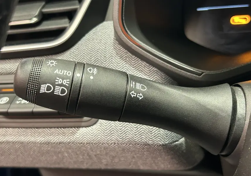 Gros plan sur la commande des phares et clignotants dans l’habitacle du Renault Clio V hybride, finition gris Rafale.