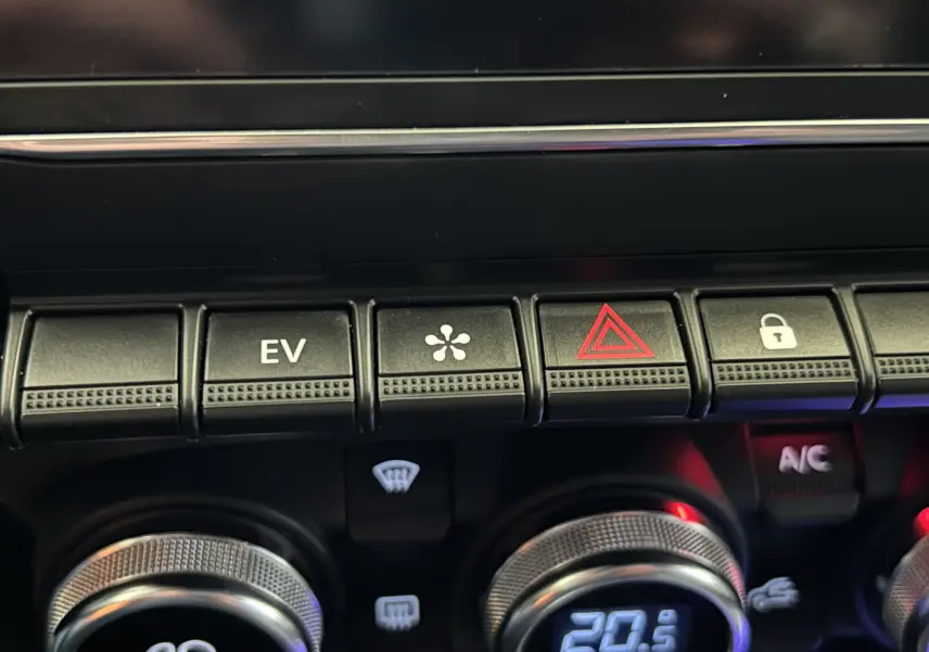Détail de la console centrale de la Renault Clio V hybride, boutons de climatisation et mode EV visibles.