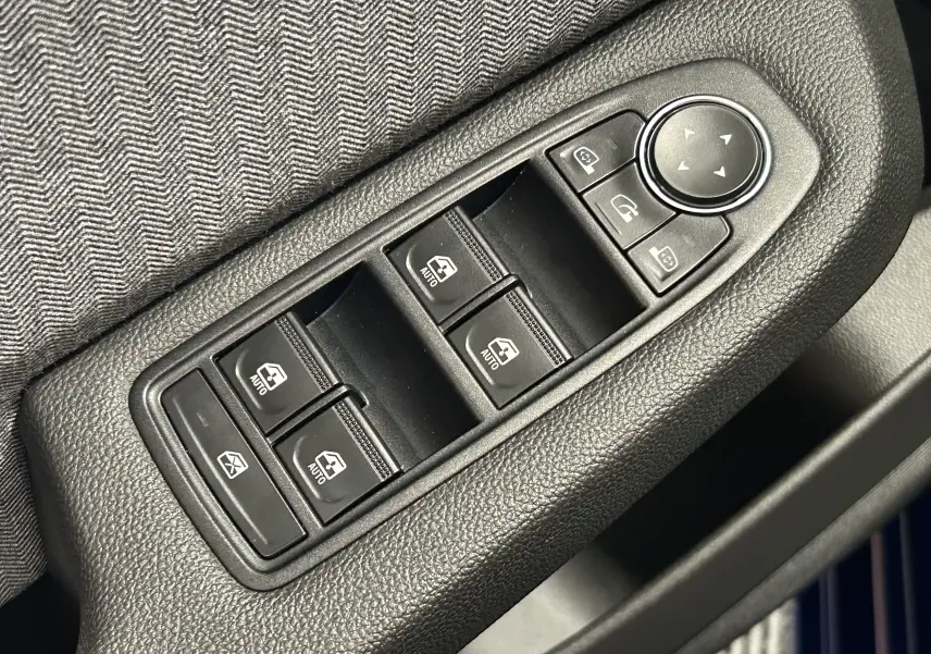Gros plan sur les commandes de lève-vitres et réglage des rétroviseurs côté conducteur d’une Renault Clio V gris Rafale Métal.