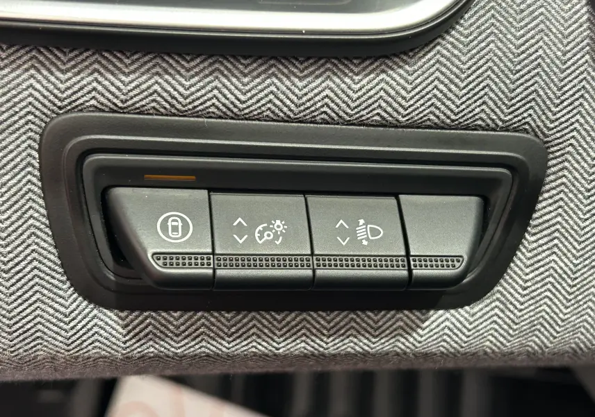 Gros plan sur les commandes de réglage d’éclairage et verrouillage dans l’habitacle gris noir de la Renault Clio V E-Tech Hybrid.