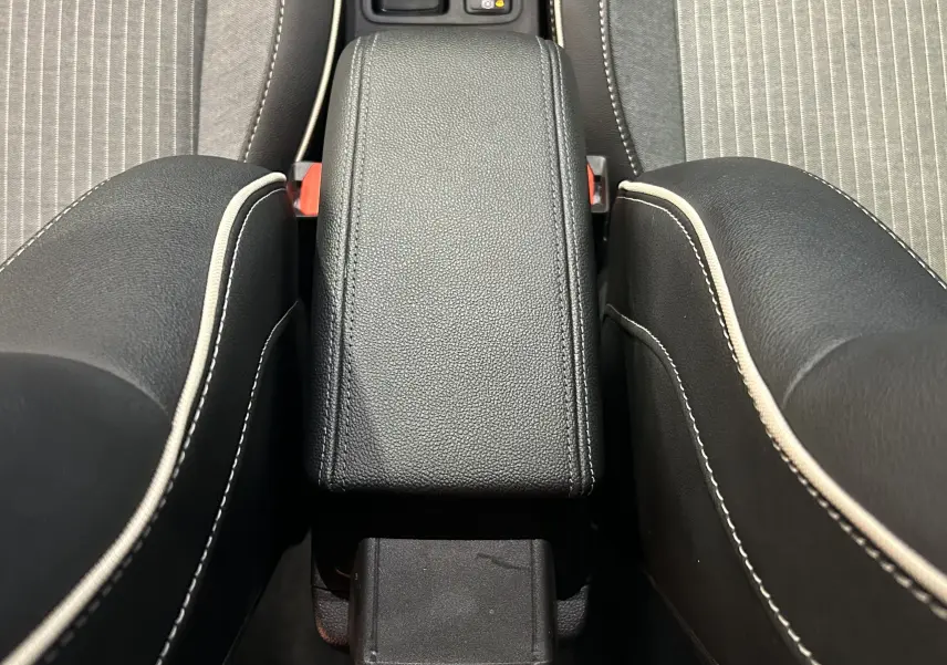 Vue rapprochée de l'accoudoir central en cuir noir avec surpiqûres blanches entre les sièges avant d'une Renault Clio V.
