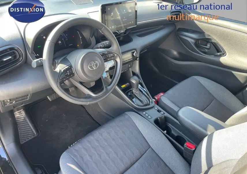 Vue intérieure côté conducteur de la Toyota Yaris Hybrid 116ch 2025 avec sièges tissu noir et tableau de bord moderne.