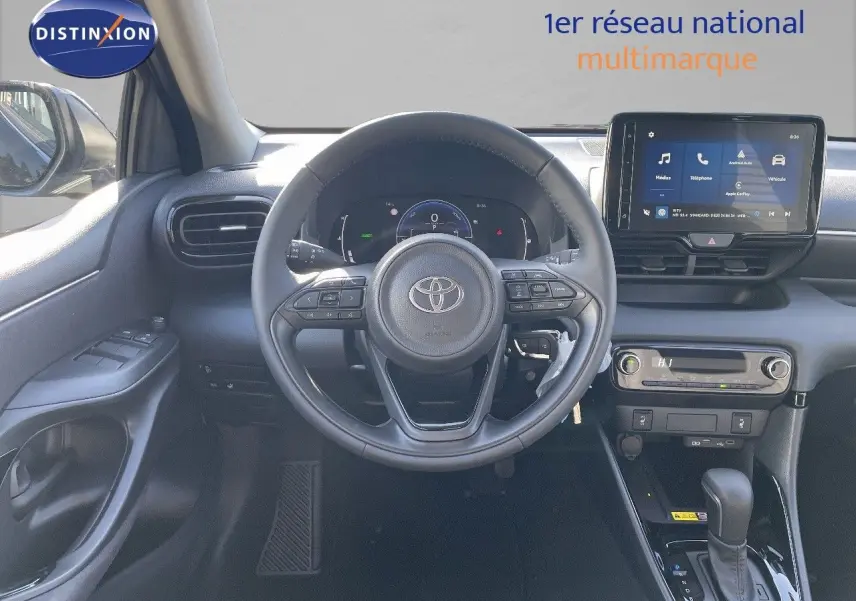 Vue intérieure avant centrée sur le volant et tableau de bord de la Toyota Yaris Hybrid 2025 en noir métal, avec écran tactile et commandes intégrées.