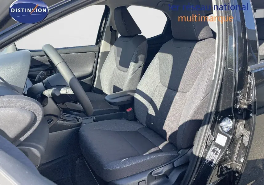 Vue intérieure côté conducteur de la Toyota Yaris Hybrid 116ch Design 2025 en noir métal, sièges tissu gris.