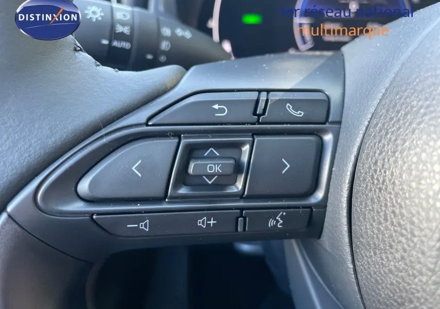 Gros plan sur les commandes au volant noir de la Toyota Yaris Hybrid 116ch 2025, avec boutons multifonctions.