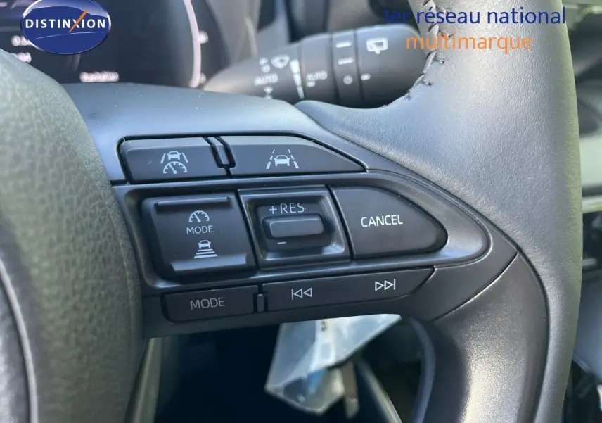 Gros plan sur les commandes au volant d'une Toyota Yaris Hybrid 2025, boutons de régulateur et aides à la conduite visibles.
