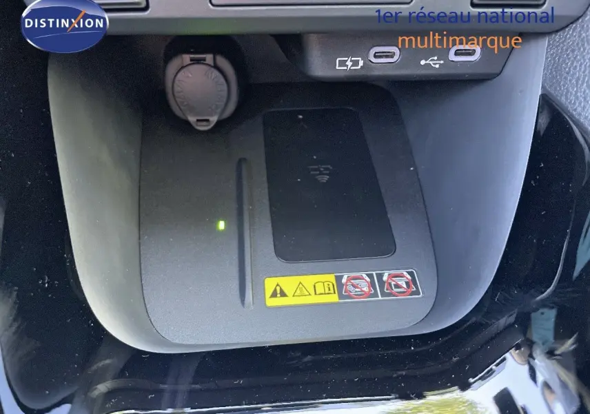 Vue rapprochée du chargeur sans fil et des ports USB dans l'habitacle noir métal de la Toyota Yaris Hybrid 2025.