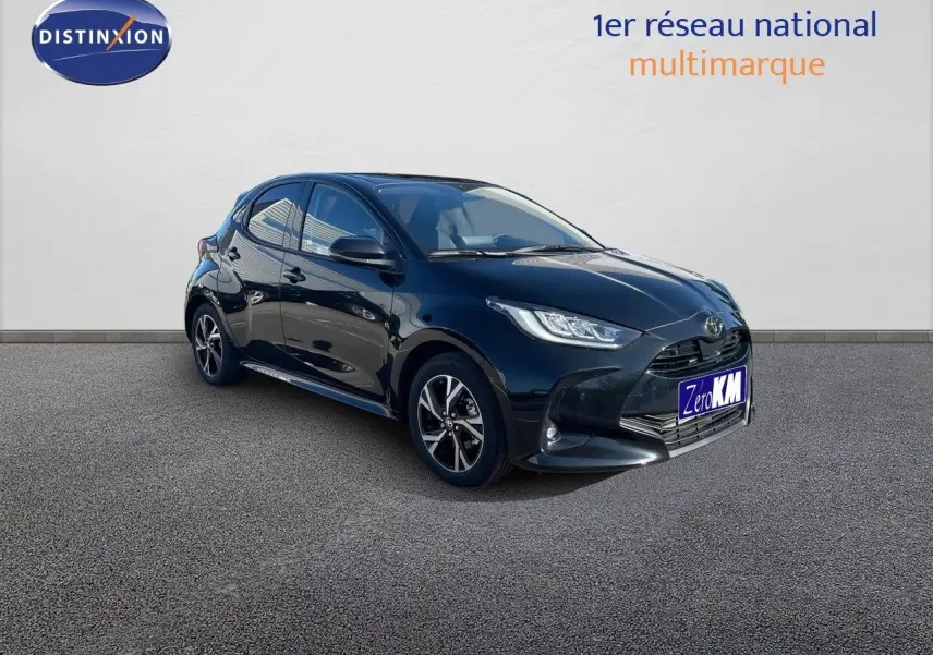 Toyota Yaris Hybrid 2025 noir métal vue 3/4 avant côté gauche avec jantes bi-ton et phares LED allumés.