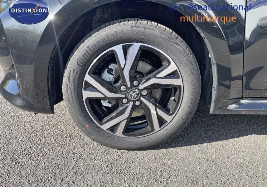 Gros plan sur la roue avant gauche noire métal d'une Toyota Yaris Hybrid 116ch 2025 avec jante alliage bicolore.