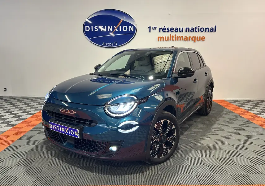 Vue 3/4 avant droite d'une FIAT 600 Hybrid 100 La Prima bleu métallisé avec phares LED allumés en showroom