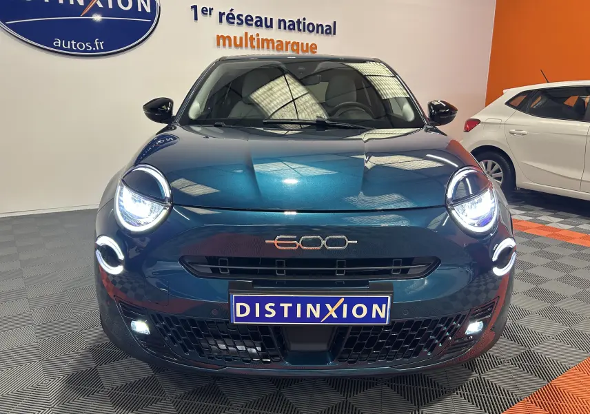 Vue frontale d'une FIAT 600 Hybrid 100 La Prima bleu avec phares LED allumés et logo 600 visible sur la calandre.