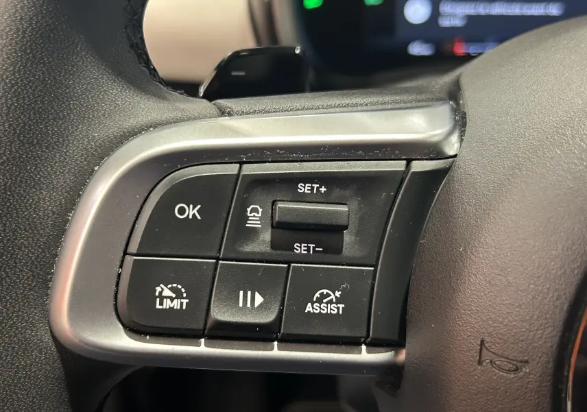 Gros plan sur les commandes de régulateur et limiteur de vitesse à gauche du volant d'une FIAT 600 Hybrid 2024.