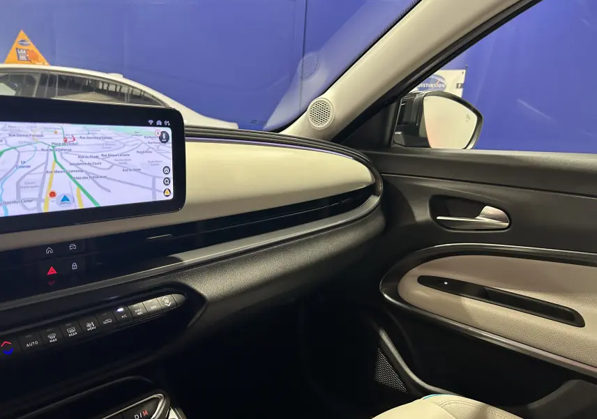 Intérieur côté passager du Fiat 600 Hybrid 2024, tableau de bord beige et noir avec écran tactile GPS visible.