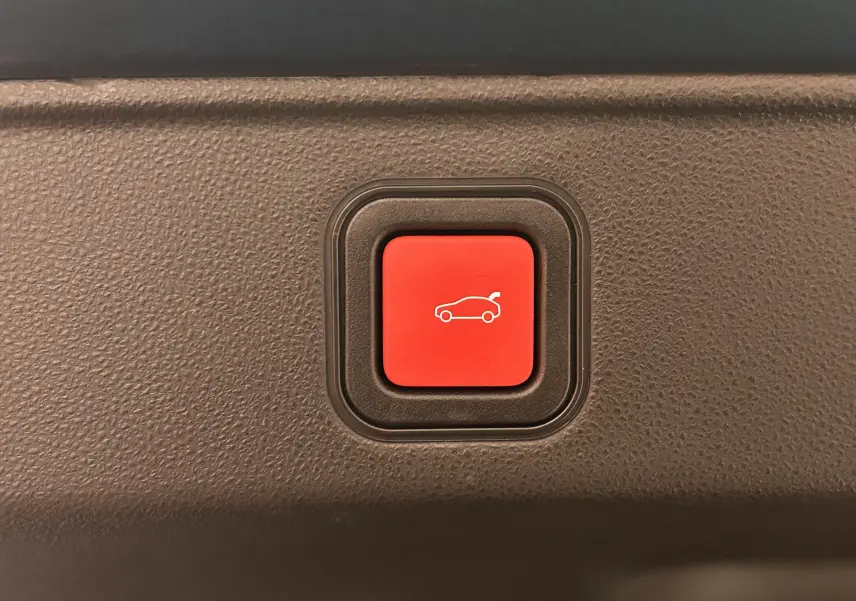 Bouton rouge d'ouverture électrique du hayon sur la planche intérieure d'une FIAT 600 Hybrid 2024 bleu.