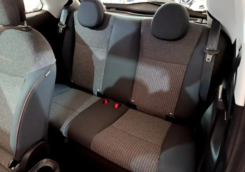 Vue intérieure arrière montrant la banquette grise à motifs rayés de la Fiat 500 42kWh Icône blanche 2022 électrique.