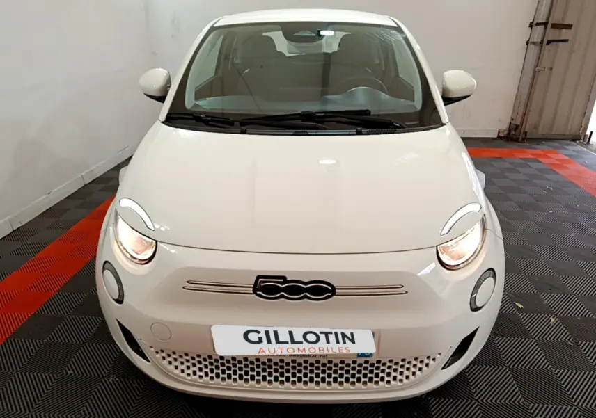 Vue avant d'une Fiat 500 électrique blanche 42kWh Icône avec phares allumés dans un garage.