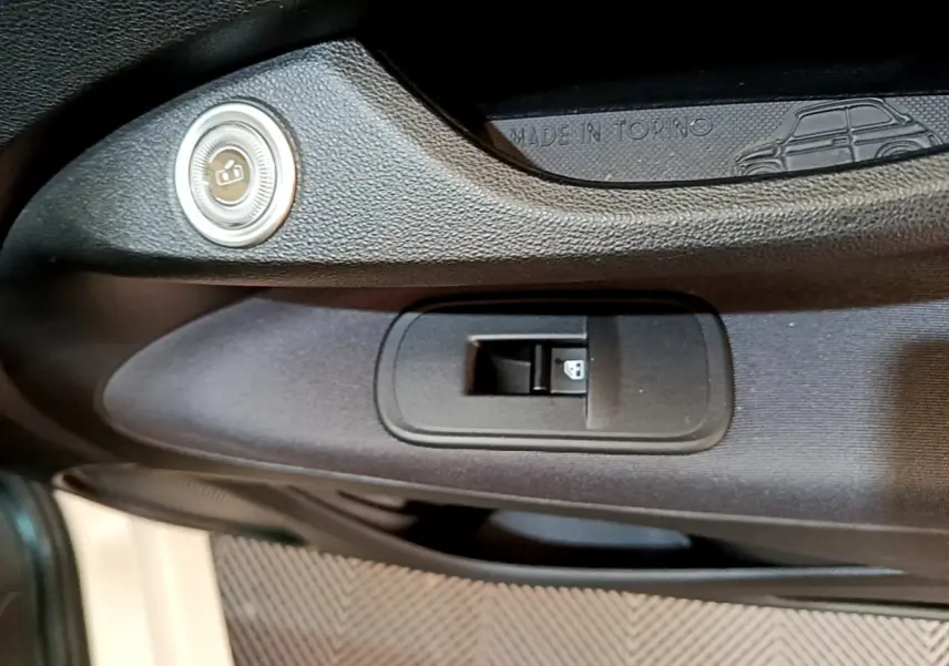 Gros plan sur la commande de verrouillage de porte côté gauche de la FIAT 500 blanche 42kWh Icône avec inscription Made in Torino.
