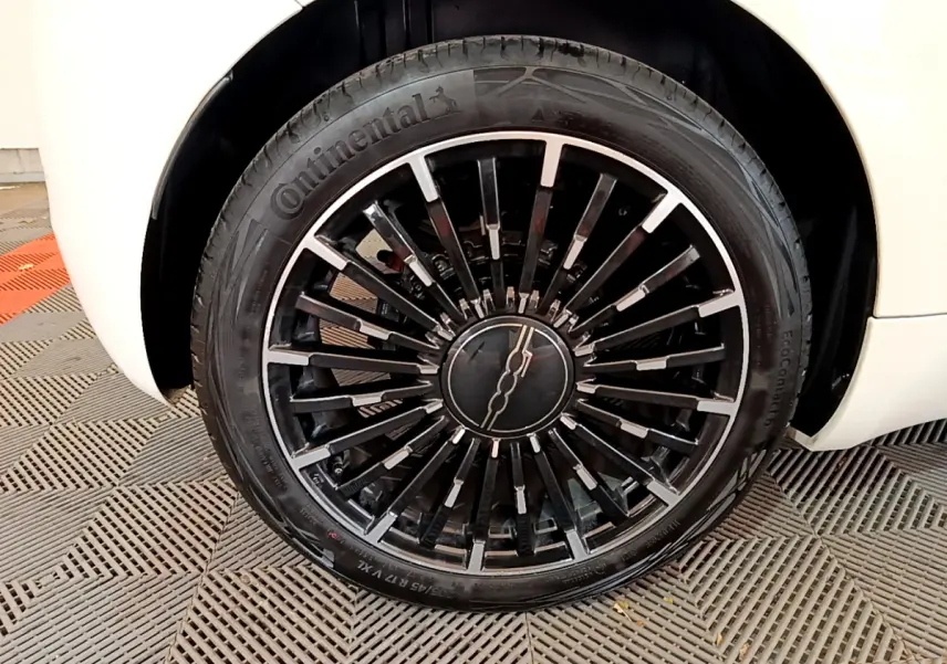 Gros plan sur la roue avant droite noire et argentée d'une FIAT 500 blanche 42kWh Icône électrique 2022.