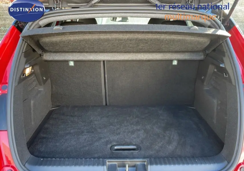 Coffre ouvert vu de l'arrière d'un Renault Captur 2025 rouge désir métal avec toit noir, montrant l'espace de chargement vide.