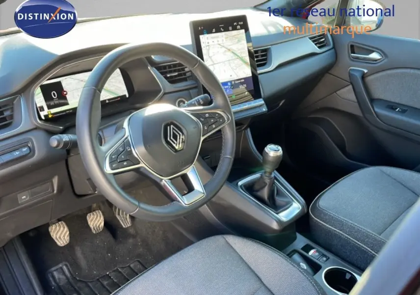 Vue intérieure du poste de conduite du Renault Captur 2025, volant multifonction et écran tactile central visibles.