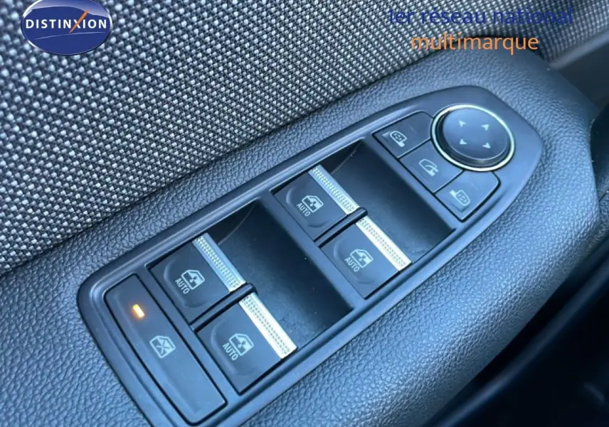 Gros plan sur les commandes des vitres électriques et rétroviseurs dans une Renault Captur rouge Désir Métal 2025.