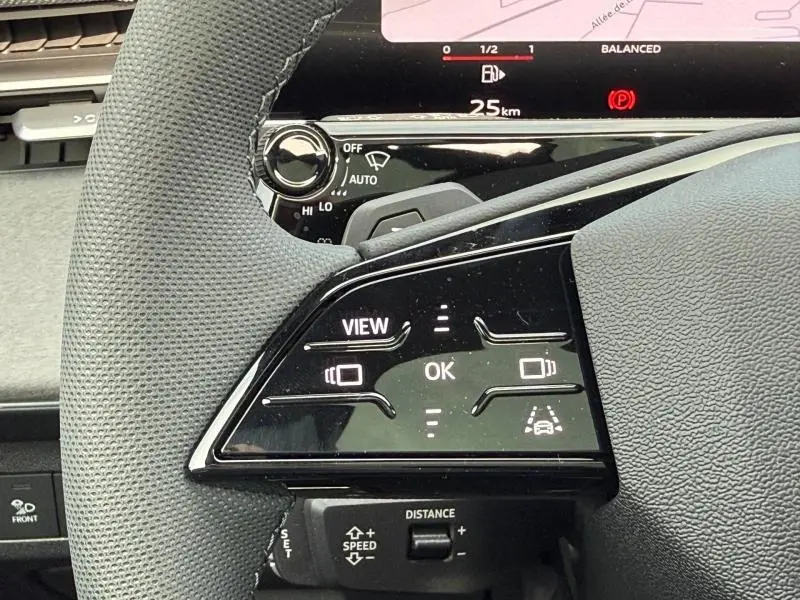 Gros plan sur les commandes au volant d’un Audi Q3 2026, avec affichage digital et finition noire brillante.