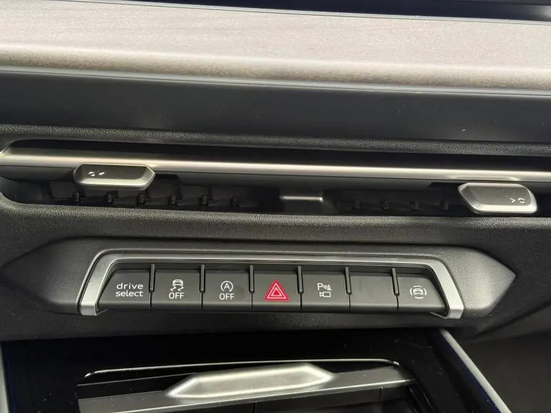 Gros plan sur la rangée de boutons de commande du tableau de bord de l'Audi Q3 2026, finition S line, avec détails en noir et argent.