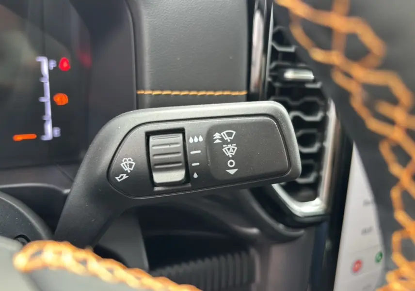 Gros plan sur la commande d’essuie-glace du Ford Ranger Wildtrak 2025 avec surpiqûres orange du volant en cuir visible.