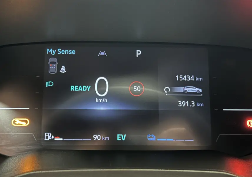 Tableau de bord numérique de Renault Clio V hybride, affichant vitesse à 0 km/h et autonomie restante, vue frontale.