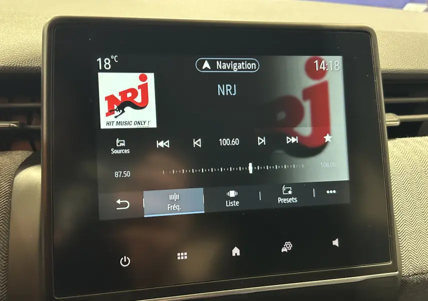 Écran tactile central de la Renault Clio V bleu iron metal affichant la radio NRJ et la navigation à 14h18.
