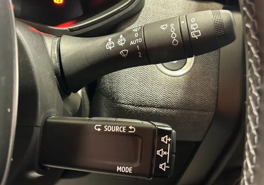 Gros plan sur les commandes au volant de la Renault Clio V, avec motifs gris et boutons de réglage audio visibles.