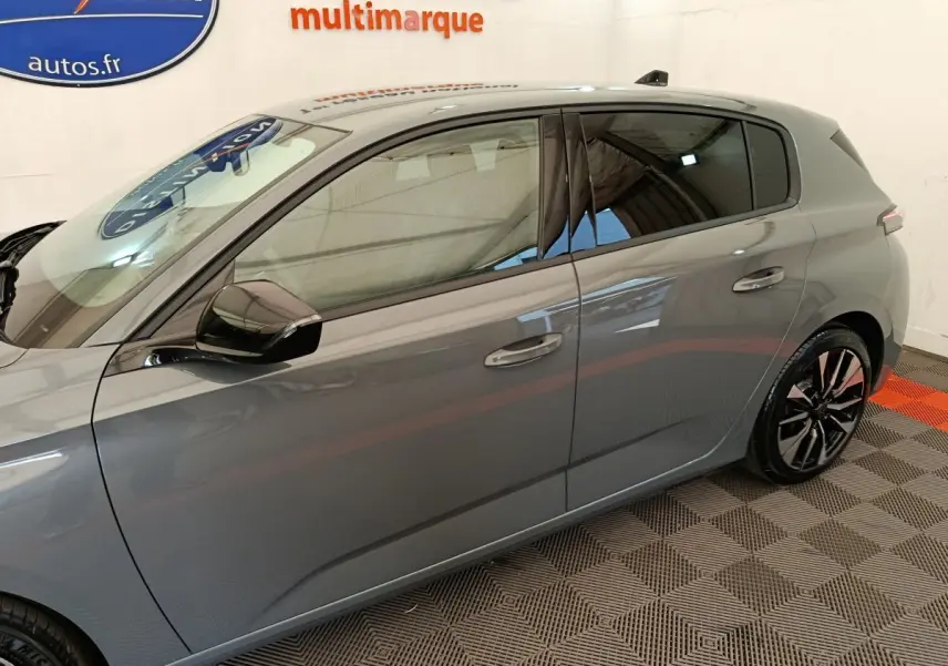 Vue latérale droite d'une Peugeot 308 gris foncé 2026 avec jantes alliage et rétroviseurs noirs.
