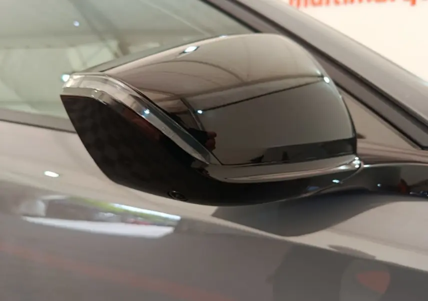 Rétroviseur droit noir brillant de la Peugeot 308 gris foncé, vue rapprochée en intérieur showroom.