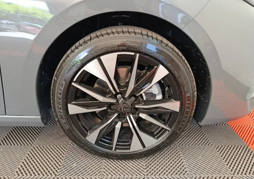 Gros plan sur la roue avant droite de la Peugeot 308 gris foncé, avec jante alliage noire et argentée au design moderne.