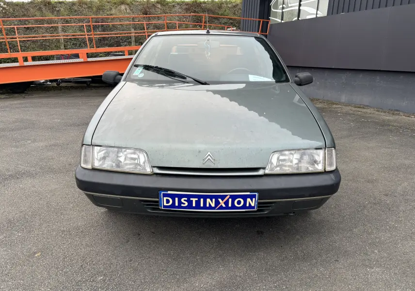 Vue frontale d'une Citroën ZX gris 1992 avec phares rectangulaires et plaque d'immatriculation Distinxion.
