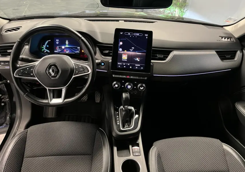 Vue intérieure avant du Renault Arkana 1.6 E-Tech Hybride 2021, tableau de bord noir avec écran tactile vertical et volant cuir.