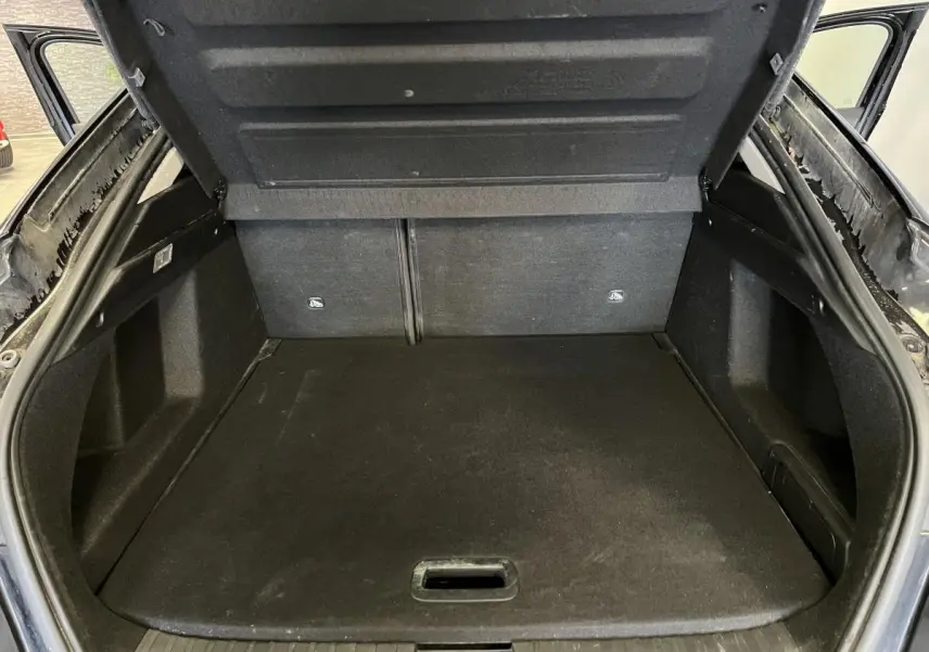 Coffre ouvert vu de l'arrière d'un Renault Arkana noir, montrant le plancher de coffre et les côtés garnis.