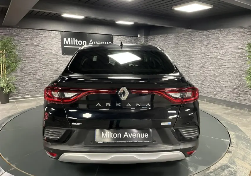 Vue arrière d'un Renault Arkana noir avec feux LED reliés et logo central dans un showroom.