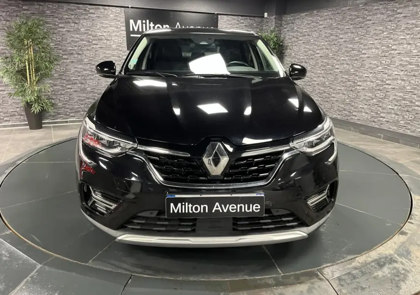 Vue frontale d'un Renault Arkana noir métal avec calandre chromée et phares Full LED Pure Vision allumés.