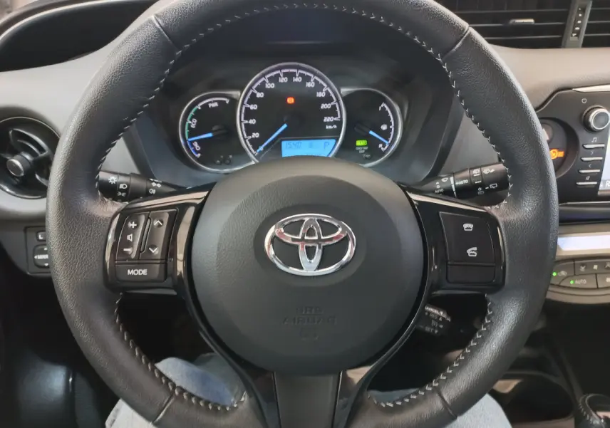 Vue rapprochée du volant en cuir noir avec commandes multifonctions de la Toyota Yaris hybride 2019.