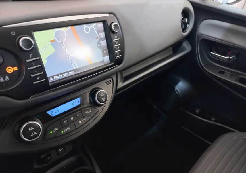 Vue intérieure côté passager de la Toyota Yaris hybride 2019, tableau de bord noir avec écran tactile et commandes climatisation.