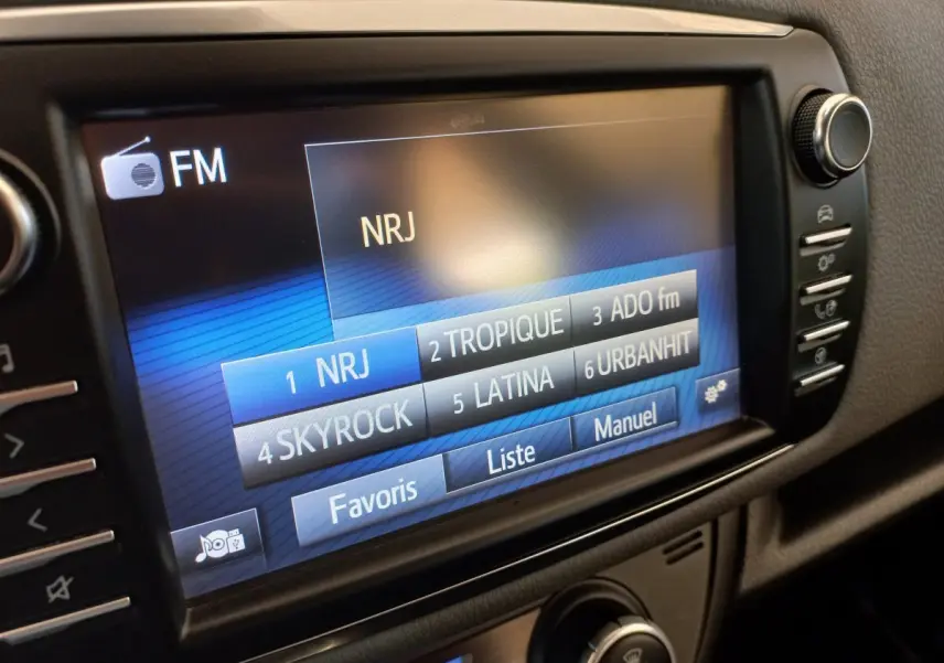 Écran tactile central de la Toyota Yaris blanche 2019 affichant les stations radio FM avec menu favoris.