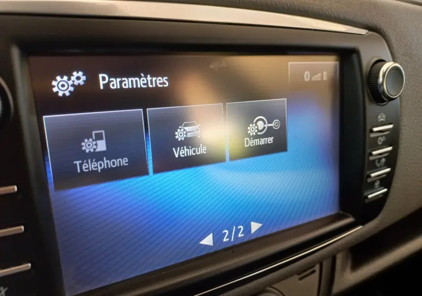 Écran tactile central affichant le menu paramètres dans l'habitacle de la Toyota Yaris hybride blanche de 2019.