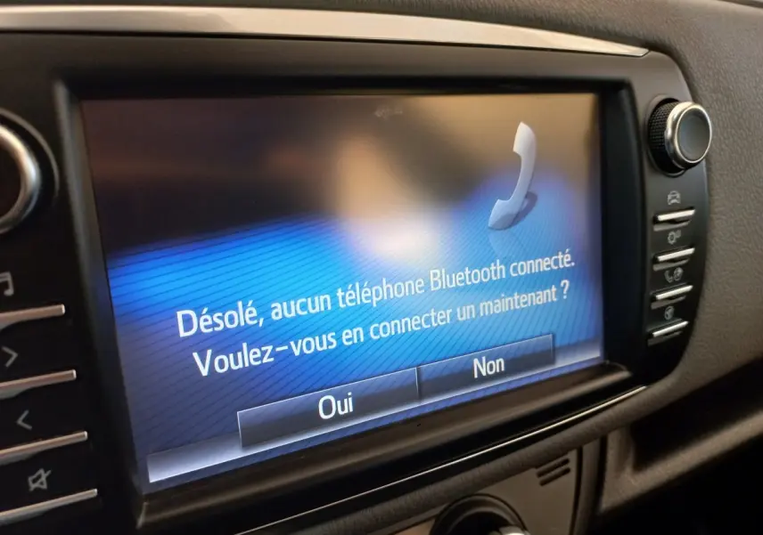 Écran tactile central affichant un message Bluetooth dans l’habitacle noir d’une Toyota Yaris blanche.