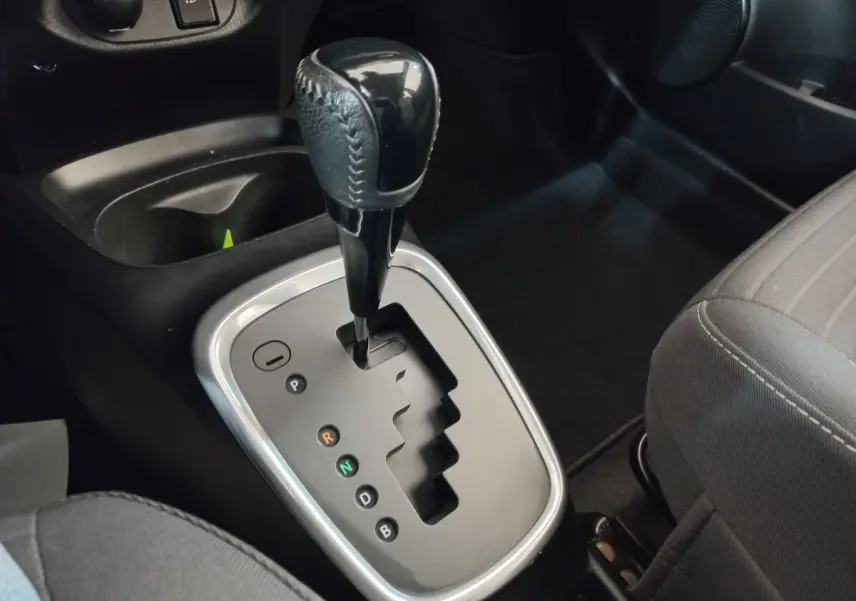 Le levier de boîte automatique noir vu de dessus dans l'habitacle sombre de la Toyota Yaris hybride blanche.