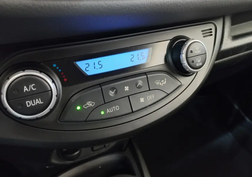 Gros plan sur la commande de climatisation bi-zone digitale de la Toyota Yaris hybride blanche, affichant 21,5°C.