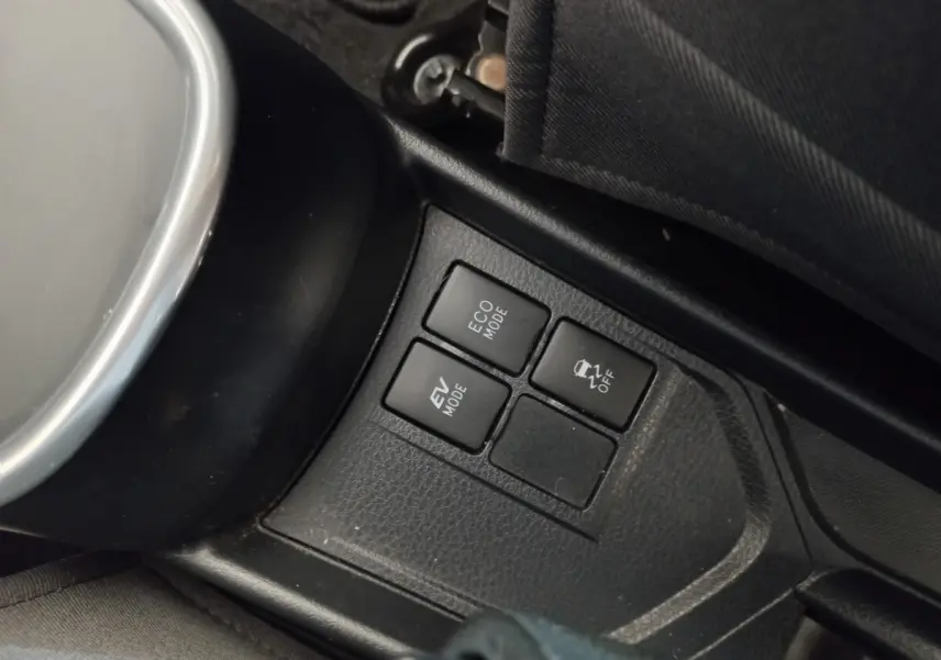 Gros plan sur les boutons de modes de conduite (ECO, EV, contrôle de stabilité) dans une Toyota Yaris hybride blanche 2019.