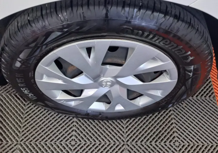 Gros plan sur la roue avant droite de la Toyota Yaris blanche, avec jante argentée et pneu Continental visible.